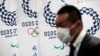 A reporter wearing a face mask stands next to the banners of the Tokyo Olympic Games during a Tokyo 2020 press conference about the spread of the new coronavirus in Tokyo on March 11, 2020. - Preparations for the Tokyo 2020 Olympics this summer are going 